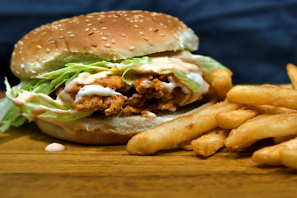 Chicken Zinger burger with crispy chicken, lettuce and sauce, beside fries