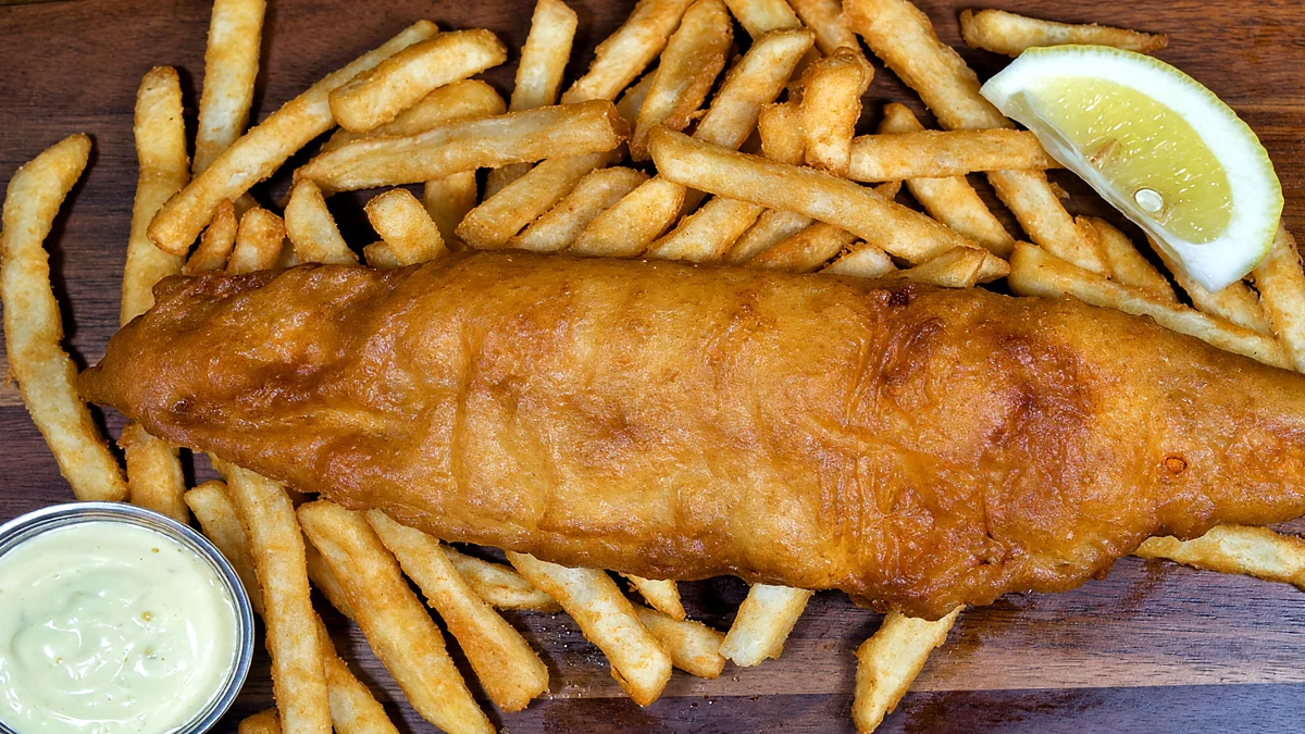 Battered halibut fillet on fries with a lemon wedge and tartar sauce